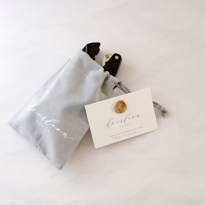 Black embosser gift wrapped in grey pouch with Heirloom Seals business card and wax seal