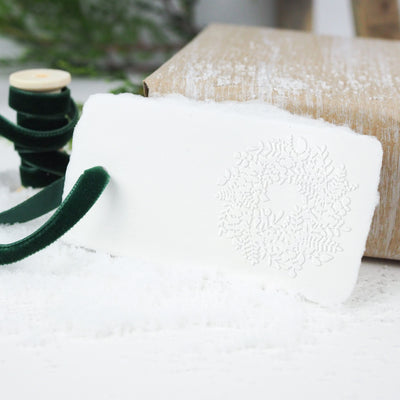White gift tag embossed with 3D Christmas wreath on a bed of snow | Heirloom Seals