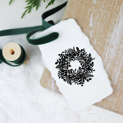 White gift tag stamped with 3D Christmas wreath tied to gift with velvet green ribbon | Heirloom Seals