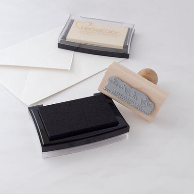 Black and cream ink pads with wooden rubber stamp on white envelope