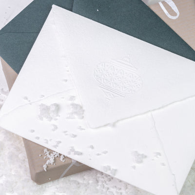 White envelope embossed with Christmas bauble on green envelope and gift | Heirloom Seals