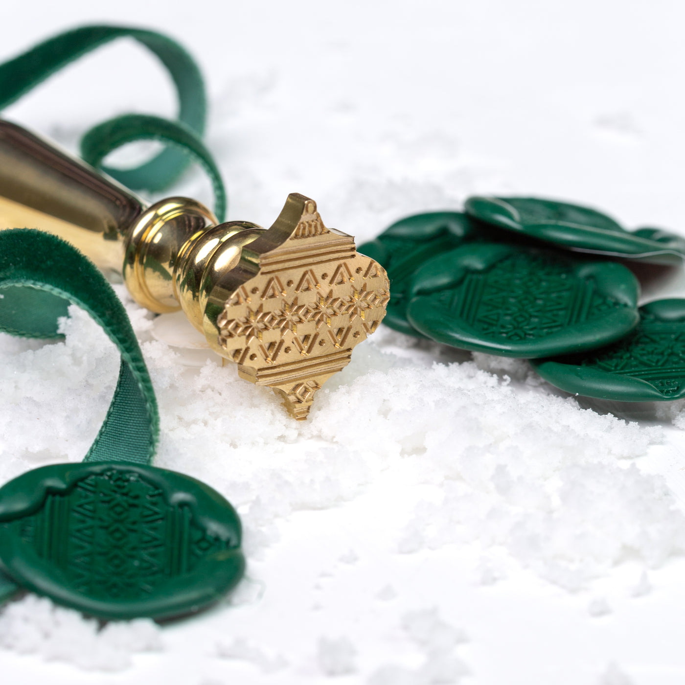 Brass bauble wax seal stamp with green wax seals on a bed of snow | Heirloom Seals