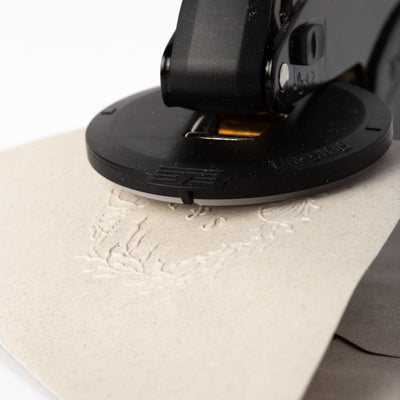 Embossing the flap of a beige envelope with a black embosser