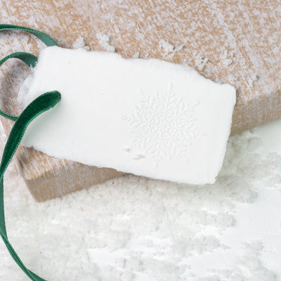 White gift tag embossed with snowflake on a wooden board and snow| Heirloom Seals