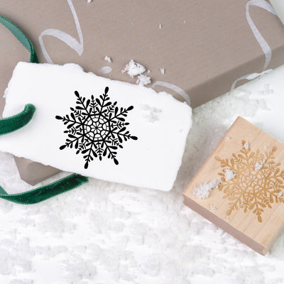 Gift tag stamped with unique snowflake on top of Christmas present and snow | Heirloom Seals