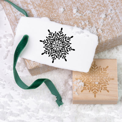 Christmas snowflake gift tag tied with green velvet ribbon and wooden rubber stamp on a bed of snow | Heirloom Seals