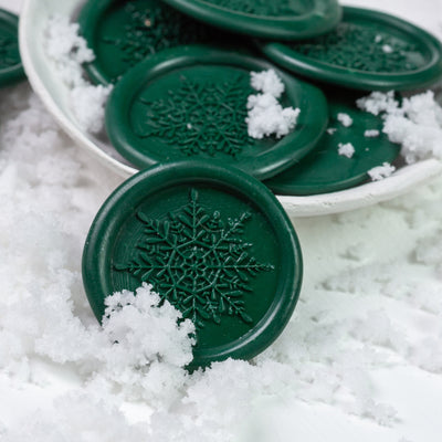 Green snowflake wax seals displayed on a bed of snow | Heirloom Seals