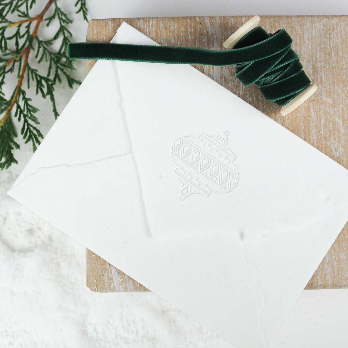 White envelope embossed with Christmas bauble and green ribbon | Heirloom Seals