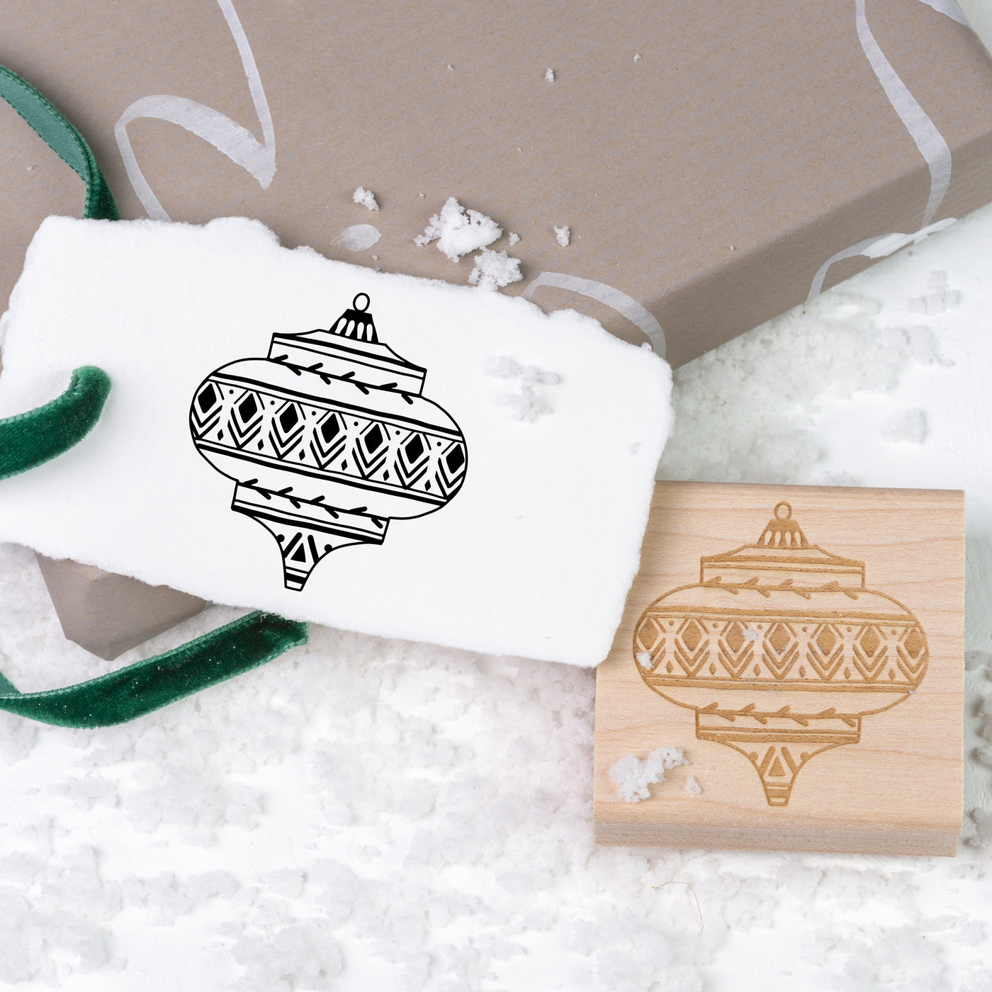 Gift tag stamped with Christmas themed bauble on top of Christmas present and snow | Heirloom Seals